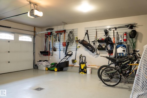 Garage with light-colored flooring, overhead lighting, and a white automatic garage door with upper window panels - 56 Highridge Way, Stony Plain, AB - Indoor Photo Showing Garage