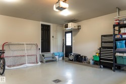 Attached garage featuring painted concrete flooring, two access doors, an overhead garage door opener, and a wall-mounted heating unit - 