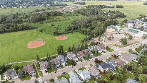 Residential neighborhood with tree-lined streets, adjacent to a park with two baseball diamonds, and a large school building - 56 Highridge Way, Stony Plain, AB - Outdoor With View