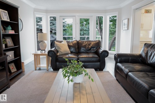 Hardwood flooring, crown molding, and large bay windows with patio door access - 56 Highridge Way, Stony Plain, AB - Indoor Photo Showing Living Room