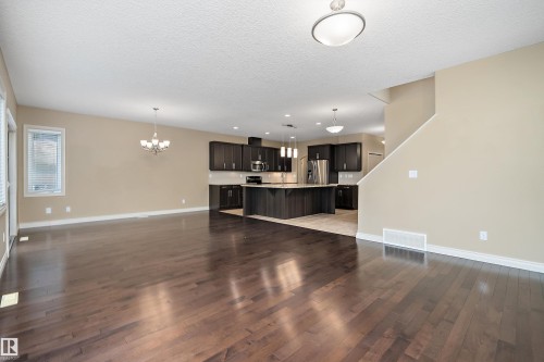 Open-concept living area featuring rich wood-finish flooring, neutral wall tones, and recessed lighting - 11203 72 Avenue Nw, Edmonton, AB - Indoor