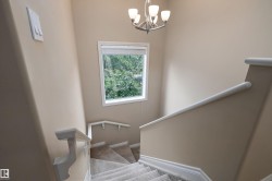 Stairway featuring neutral wall finishes, white trim, and a contemporary chandelier - 