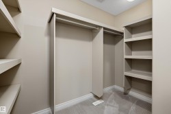 Walk-in closet featuring built-in shelving, hanging rods, neutral wall color, white baseboards, and patterned carpet flooring - 