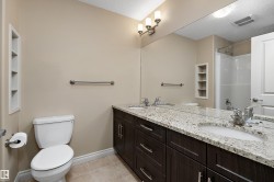 Bathroom featuring a dual-sink vanity with granite countertop and dark wood-finish cabinetry - 