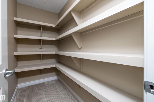 Walk-in pantry featuring light-toned walls, multiple levels of white shelving, patterned flooring, and white baseboards - 11203 72 Avenue Nw, Edmonton, AB - Indoor With Storage