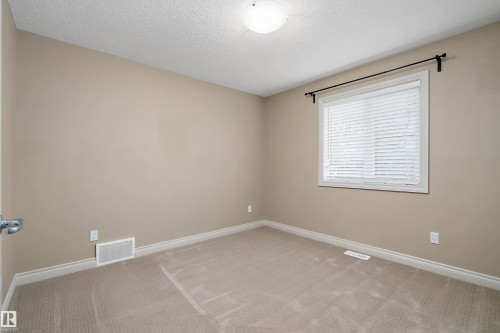 Carpeted room featuring a window with horizontal blinds, a ceiling-mounted light fixture, and neutral wall tones - 11203 72 Avenue Nw, Edmonton, AB - Indoor Photo Showing Other Room