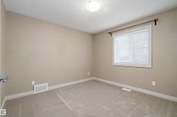 Carpeted room featuring a window with horizontal blinds, a ceiling-mounted light fixture, and neutral wall tones - 
