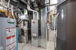 Utility room featuring two water heaters, a furnace, and ductwork - 