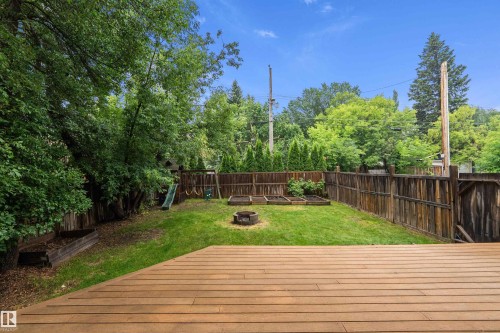 Expansive backyard featuring a wood-finish deck, lush lawn, and mature perimeter trees - 11203 72 Avenue Nw, Edmonton, AB - Outdoor With Backyard