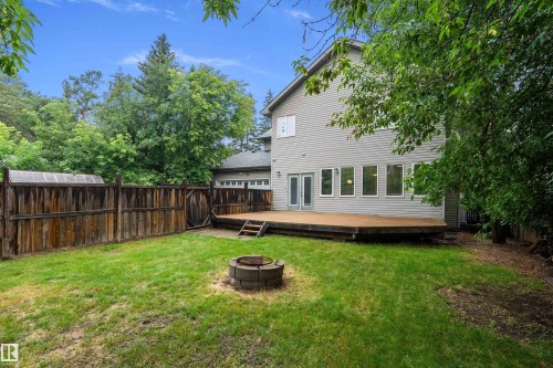 Rear exterior featuring a spacious wood deck with steps to the lawn, multiple large windows, and double doors - 11203 72 Avenue Nw, Edmonton, AB - Outdoor