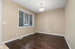 Spacious room featuring wood-finish flooring, neutral wall tones, white trim, and a large window with privacy blinds - 