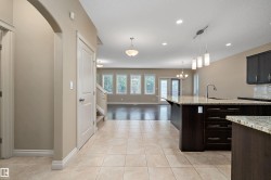 Spacious kitchen featuring an expansive island with a stone-finish countertop, undermount sink, and pendant lighting - 