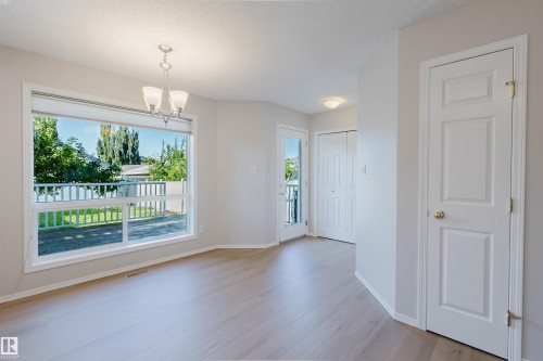 Light wood-finish flooring throughout, large picture window, multi-pane glass door, and a built-in closet with bifold doors - 21332 89 Avenue Nw, Edmonton, AB - Indoor Photo Showing Other Room