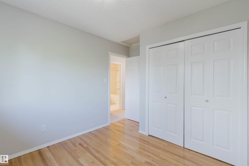 Light-colored hardwood flooring, neutral wall tones, and white bi-fold closet doors - 21332 89 Avenue Nw, Edmonton, AB - Indoor Photo Showing Other Room