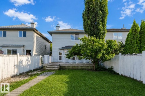 Expansive green lawn with a paver walkway, leading to a wooden deck with white railings - 21332 89 Avenue Nw, Edmonton, AB - Outdoor With Deck Patio Veranda