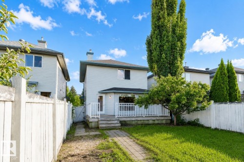 Rear exterior featuring a deck with white railings, a ground-level patio, a paved pathway, and a grassy yard - 21332 89 Avenue Nw, Edmonton, AB - Outdoor With Deck Patio Veranda