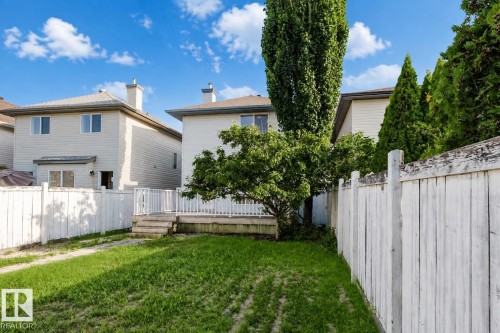 Spacious backyard with mature landscaping, including established trees and manicured lawn, enclosed by white vinyl fencing - 21332 89 Avenue Nw, Edmonton, AB - Outdoor