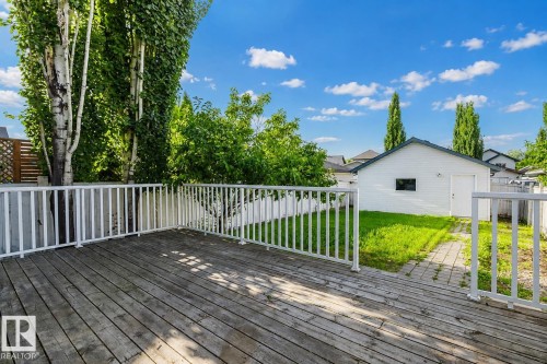 Expansive wood deck with white railings, featuring a detached garage and a paved pathway - 21332 89 Avenue Nw, Edmonton, AB - Outdoor With Deck Patio Veranda