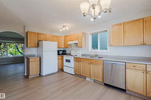 Kitchen featuring light wood cabinetry, light countertops, wood-finish flooring, and an arched doorway - 21332 89 Avenue Nw, Edmonton, AB - Indoor Photo Showing Kitchen With Double Sink