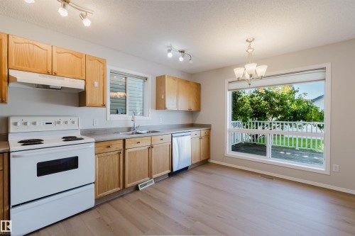 Kitchen featuring light wood-finish cabinetry, a white range, and a stainless steel dishwasher - 21332 89 Avenue Nw, Edmonton, AB - Indoor Photo Showing Kitchen With Double Sink