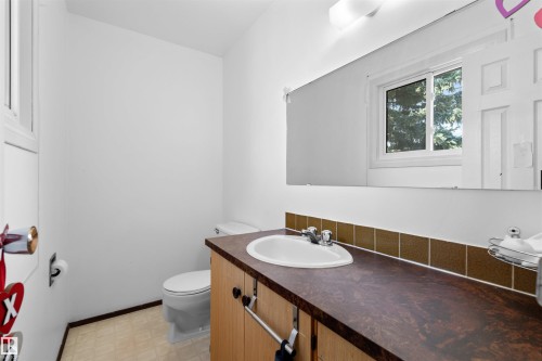White vanity with an integrated sink, brown countertop, and tile backsplash - 2730 105 Street Nw, Edmonton, AB - Indoor Photo Showing Bathroom