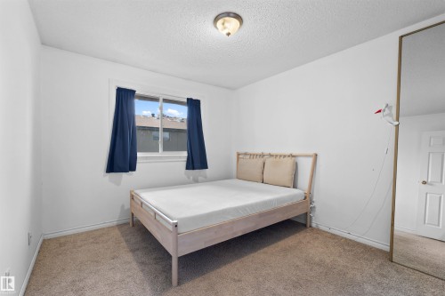 Carpeted flooring, white painted walls, and a single window with blue curtains - 2730 105 Street Nw, Edmonton, AB - Indoor Photo Showing Bedroom
