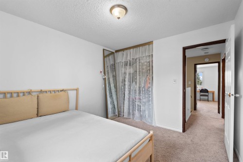 Wall-to-wall carpeting and white walls with a built-in closet featuring mirrored doors - 2730 105 Street Nw, Edmonton, AB - Indoor Photo Showing Bedroom