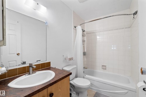 Integrated bathtub and shower with white subway tile surround, single vanity with oval sink, and mounted mirror with strip lighting - 2730 105 Street Nw, Edmonton, AB - Indoor Photo Showing Bathroom