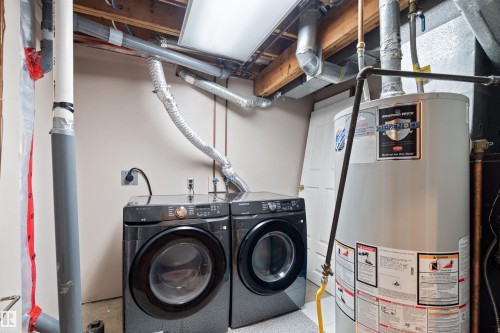 Laundry area with a water heater and exposed overhead utility lines - 2730 105 Street Nw, Edmonton, AB - Indoor Photo Showing Laundry Room