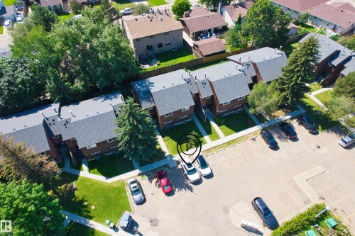 Multi-unit residential structure with dark shingle roofing, brick exterior, and landscaped grounds featuring mature trees and green spaces - 2730 105 Street Nw, Edmonton, AB - Outdoor With View
