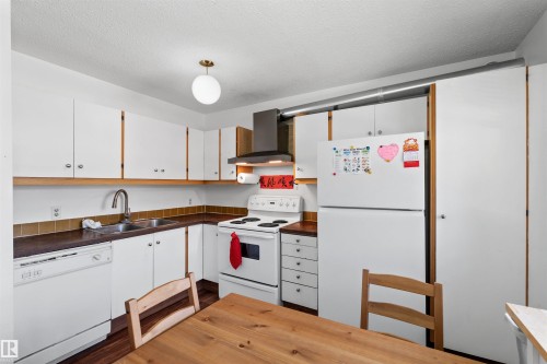 White cabinetry with brushed nickel hardware, wood-finish countertops, stainless steel double basin sink, and tile backsplash - 2730 105 Street Nw, Edmonton, AB - Indoor Photo Showing Kitchen With Double Sink