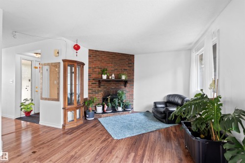 Wood-finish flooring throughout, featuring a brick fireplace with a wood mantle, and white walls - 2730 105 Street Nw, Edmonton, AB - Indoor With Fireplace