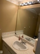 Vanity with integrated sink, chrome faucet, and expansive mirror with overhead lighting - 
