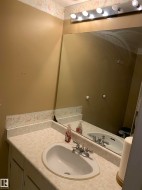 Vanity with an integrated sink, dual-handle chrome faucet, and a large wall-mounted mirror - 