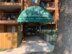 Building entry featuring a green awning, glass double doors, and adjacent wood-paneled walls - 