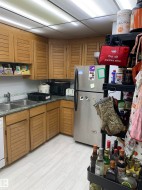 Wood-finish cabinetry with louvered doors, light-toned wood-finish flooring, and a stainless steel refrigerator - 