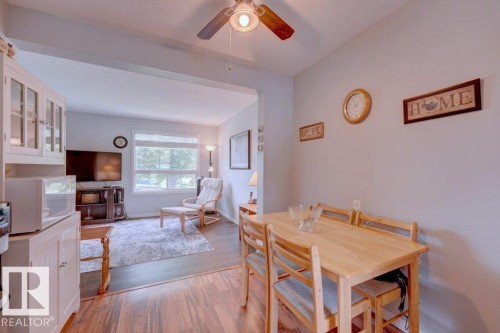 Wood-finish flooring throughout, featuring a dining area with a wood-tone table and a living area with a large window - 307 Northgate Terrace Nw, Edmonton, AB - Indoor Photo Showing Dining Room