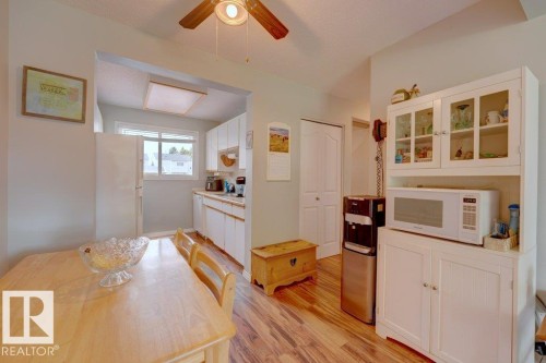 Wood-finish flooring throughout, white kitchen cabinetry, a window over the kitchen sink, and a built-in pantry cabinet with glass-front uppers - 307 Northgate Terrace Nw, Edmonton, AB - Indoor