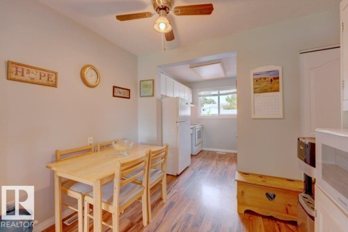 Wood-finish flooring throughout, with a ceiling fan light fixture and recessed lighting in the kitchen area - 307 Northgate Terrace Nw, Edmonton, AB - Indoor Photo Showing Dining Room