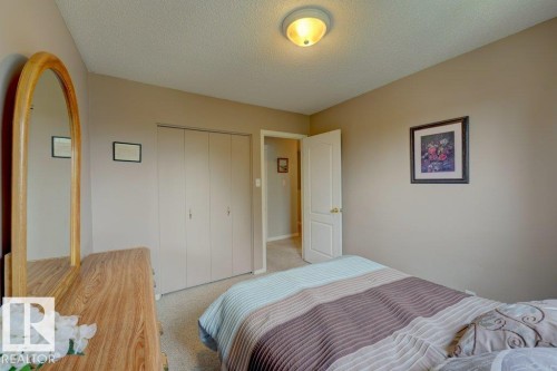 Spacious bedroom featuring warm wood-finish flooring, dual closets with white panel doors, and soft neutral wall tones - 307 Northgate Terrace Nw, Edmonton, AB - Indoor Photo Showing Bedroom