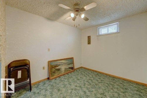 Recessed window with blinds, ceiling fan with integrated lighting, textured ceiling, light-toned walls, and green carpeting - 307 Northgate Terrace Nw, Edmonton, AB - Indoor Photo Showing Other Room