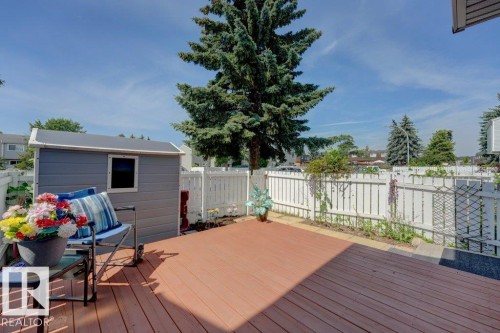 Expansive outdoor deck featuring wood-finish flooring, a white privacy fence, a detached storage shed, and mature trees - 307 Northgate Terrace Nw, Edmonton, AB - Outdoor With Deck Patio Veranda
