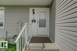 Gray horizontal siding with a white entry door, an exterior wall light fixture, and white porch railings - 