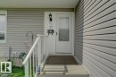 Gray horizontal siding with a white entry door, an exterior wall light fixture, and white porch railings - 307 Northgate Terrace Nw, Edmonton, AB  - Outdoor With Exterior 