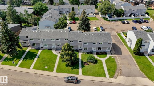 Modern townhome community featuring clean-lined architecture with multiple windows, manicured front lawns with mature landscaping, and generous green spaces throughout the development - 307 Northgate Terrace Nw, Edmonton, AB - Outdoor With View
