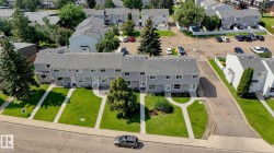 Modern townhome community featuring clean-lined architecture with multiple windows, manicured front lawns with mature landscaping, and generous green spaces throughout the development - 