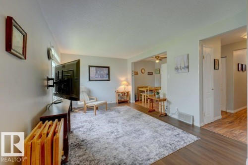 Spacious room with dark wood-finish flooring, light-colored walls, and a recessed dining area beyond - 307 Northgate Terrace Nw, Edmonton, AB - Indoor