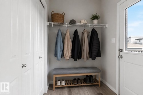Entryway featuring wood-finish flooring, two white bi-fold closets, a white door with a window, and a built-in wire shelf with hanging rod - 2355 Kelly Circle Circle Sw, Edmonton, AB - Indoor