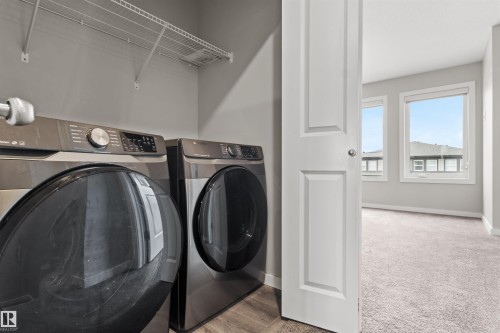 Dedicated laundry area featuring wire shelving and wood-finish flooring - 2355 Kelly Circle Circle Sw, Edmonton, AB - Indoor Photo Showing Laundry Room