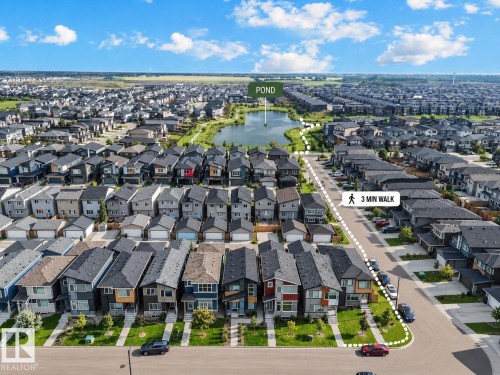 Aerial perspective of a developed residential area featuring a central pond, paved roadways, and uniform detached homes with landscaped frontages - 2355 Kelly Circle Circle Sw, Edmonton, AB - Outdoor With View